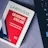 A paperback book titled 'Grammaire Anglaise' by Larousse lies on a soft, gray surface next to a black laptop keyboard with visible Intel logo. The book has a red, white, and blue cover with text in French emphasizing essential grammar modules.